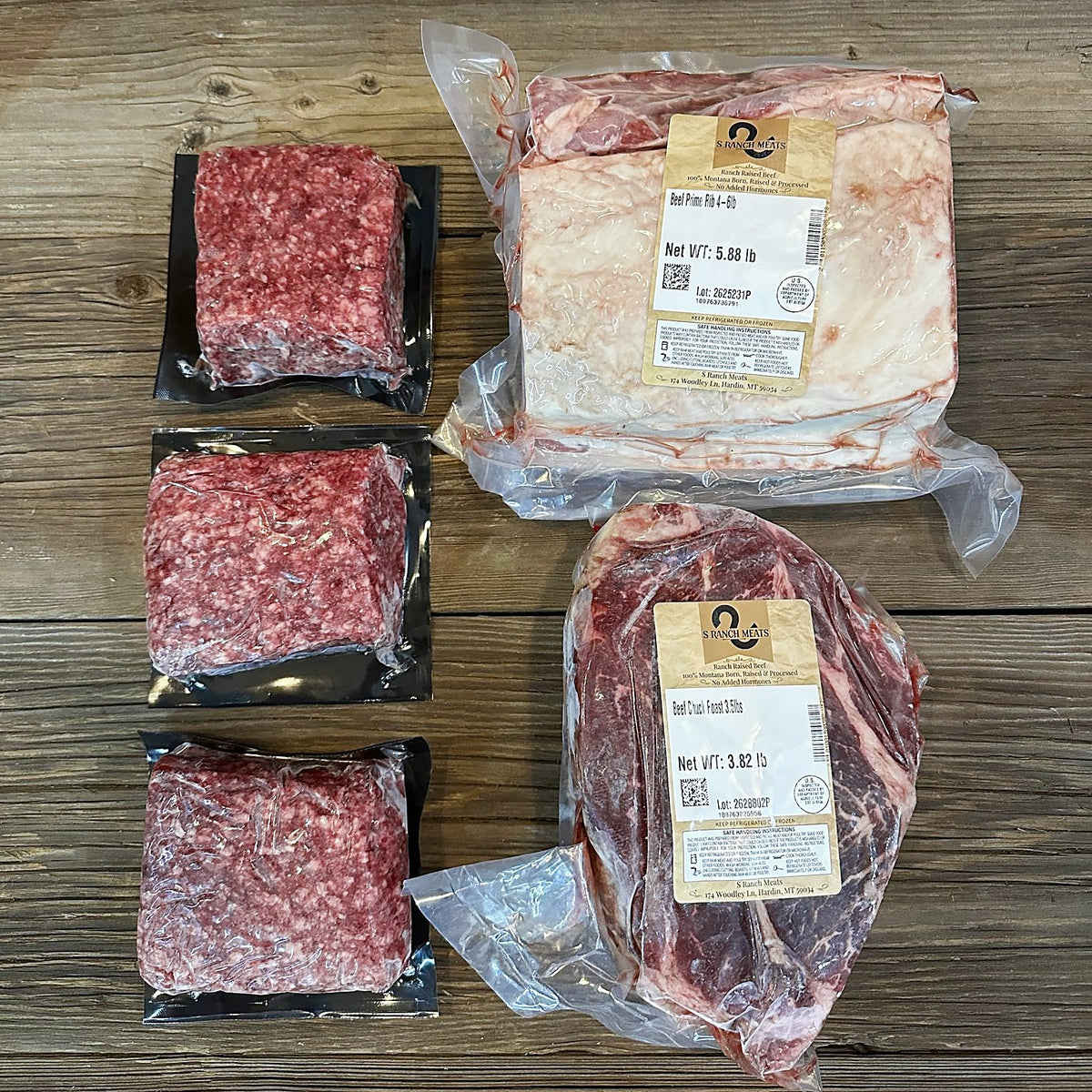 Boneless prime rib roast, chuck roast and three packs of ground beef on a wood table