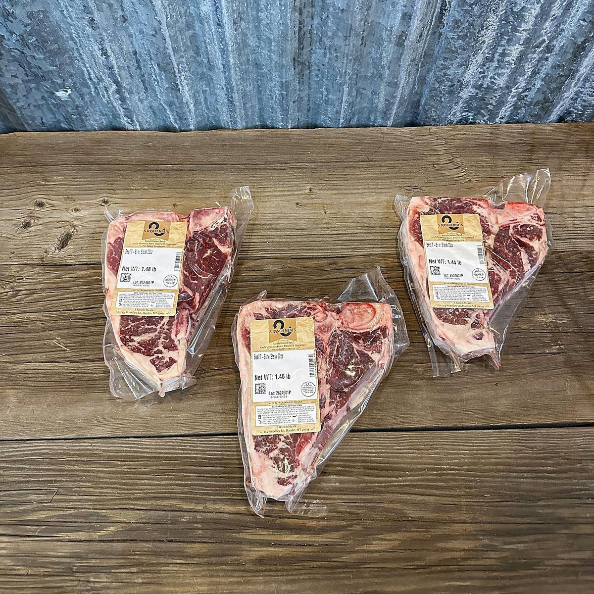 Three 22 oz T-bone steaks laid out on a wood table