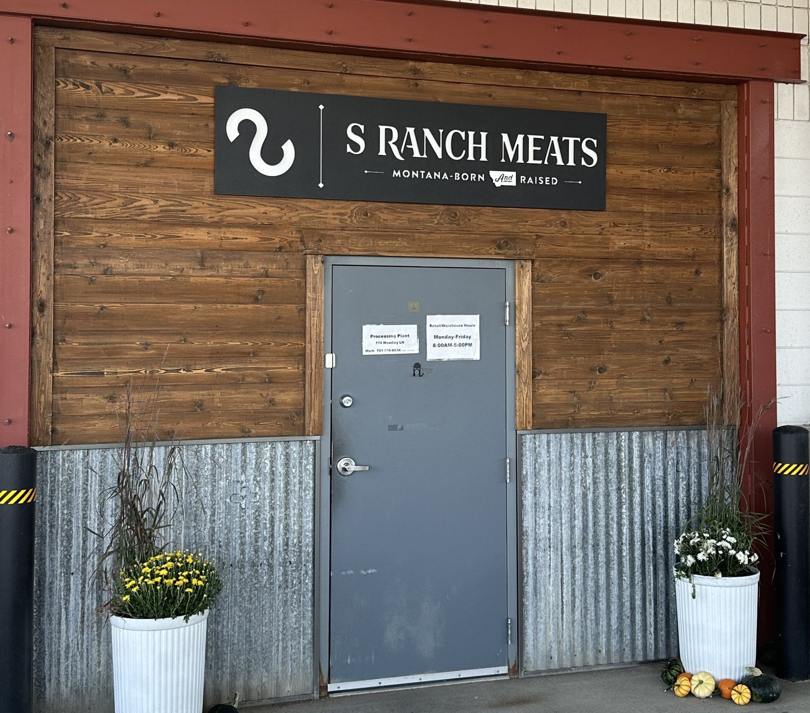 S Ranch Meats storefront in Hardin, Montana: the S Ranch Meats sign over the door with fall mums on either side