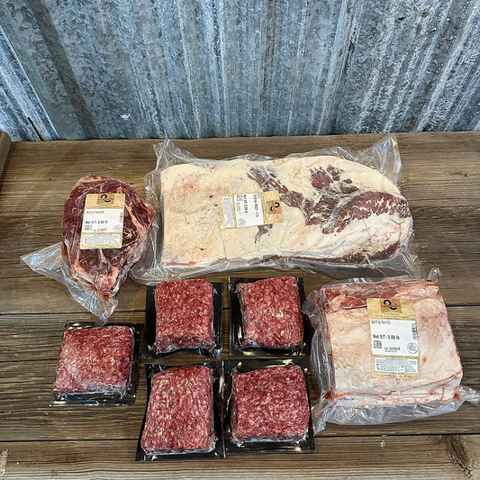 Prime rib roast, whole brisket, chuck roast and five packs of ground beef on a wood table