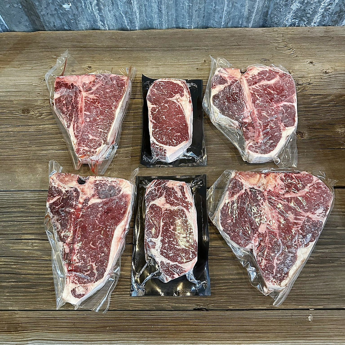 Two porterhouses, two T-bones and two ribeyes on a wood table