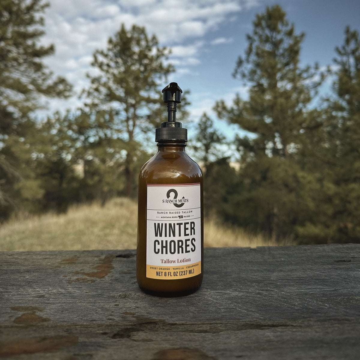 Winter Chores tallow lotion pump bottle against a Montana winter sky