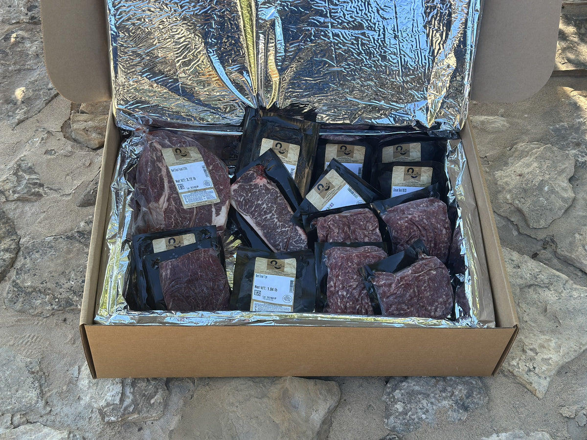 S Ranch Meats insulated shipping box opened on Montana rock, vacuum-sealed beef inside the foil liner