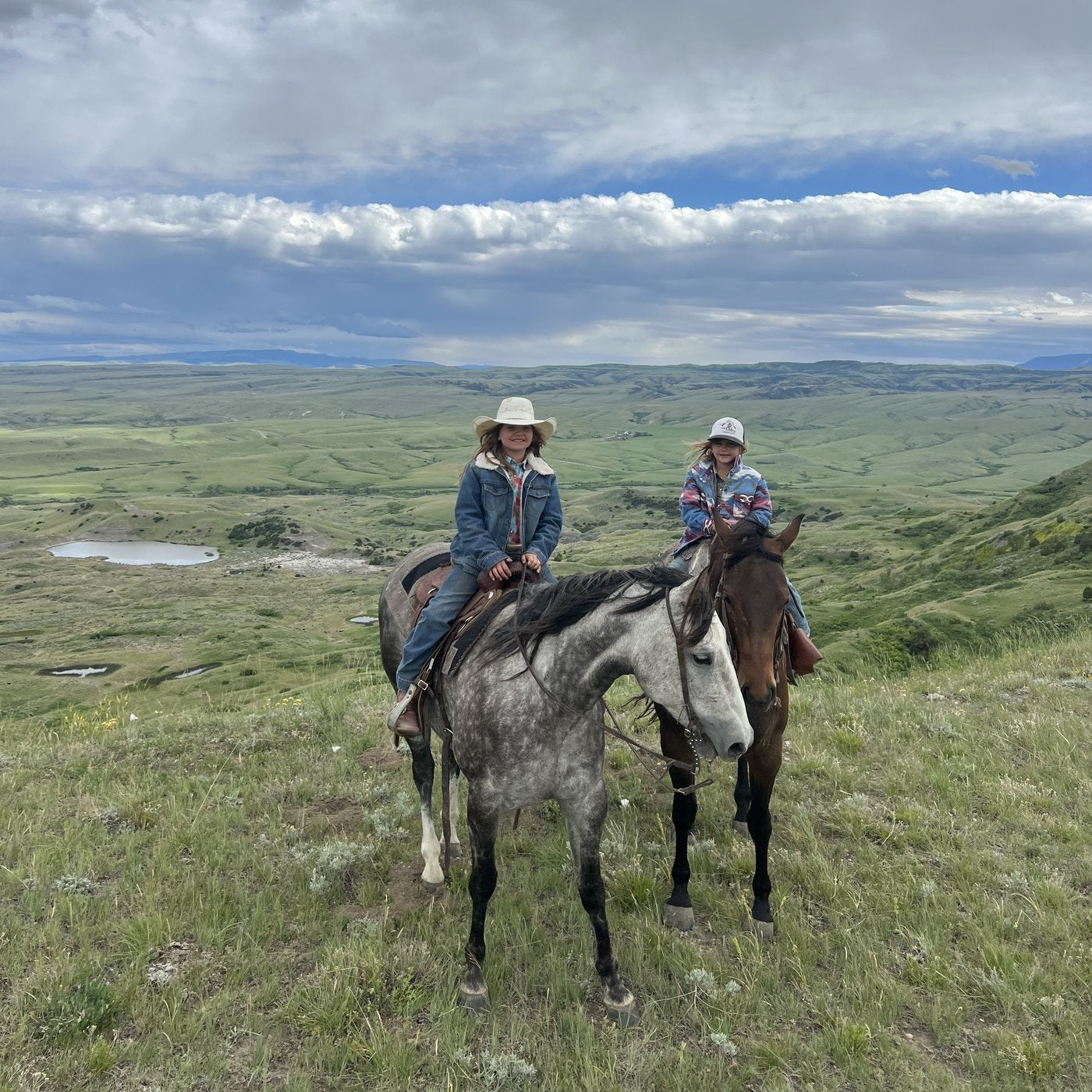 Two of the Scott kids horseback above the valley on the S Ranch